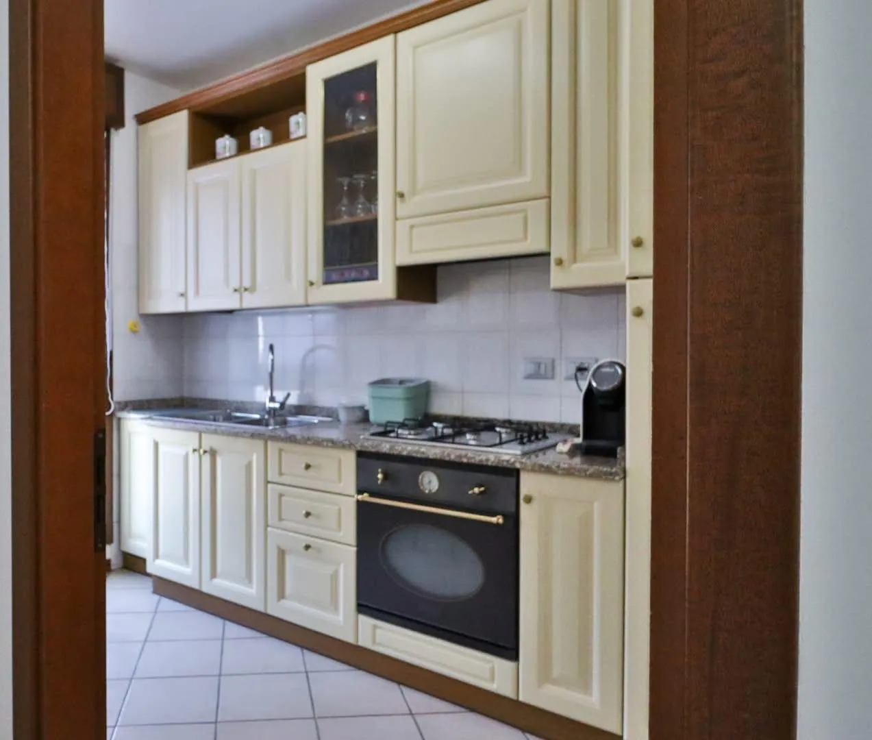 Cucina con fornelli, forno, lavello e mobili chiari